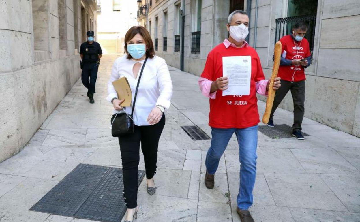 Bonig, del PP, llega a Les Corts acompañada por un manifestante contra la ley del juego.