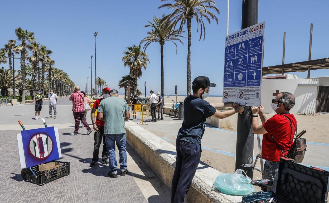 Operarios colocan los nuevos carteles informativos ayer en las playas del norte de la ciudad.