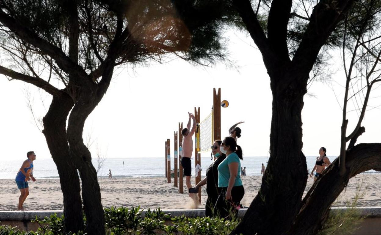 Personas paseando ante una playa valenciana.