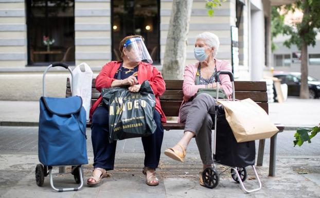 Dos mujeres descansan sentadas en un banco en Barcelona. 