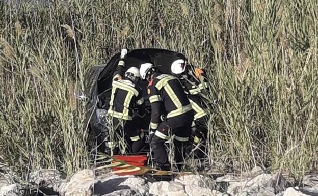 Imagen principal - Una mujer herida tras chocar su coche con un camión y caer a la orilla del río Turia