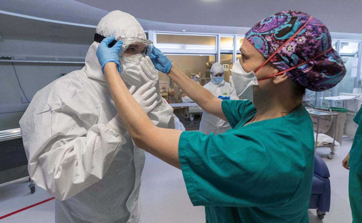 Una enfermera coloca unas gafas al médico de UCI.