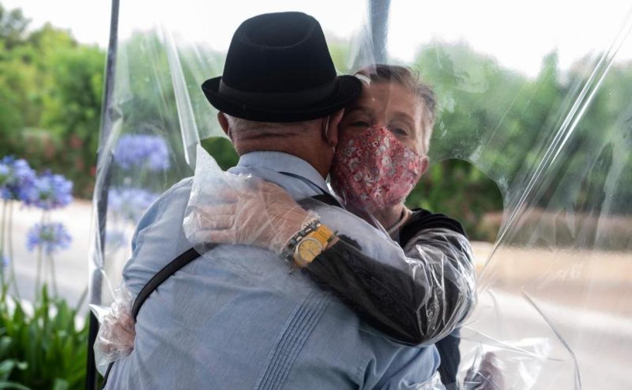 Una mujer abraza a su padre con un plástico creado para permitir el contacto entre familiares. 