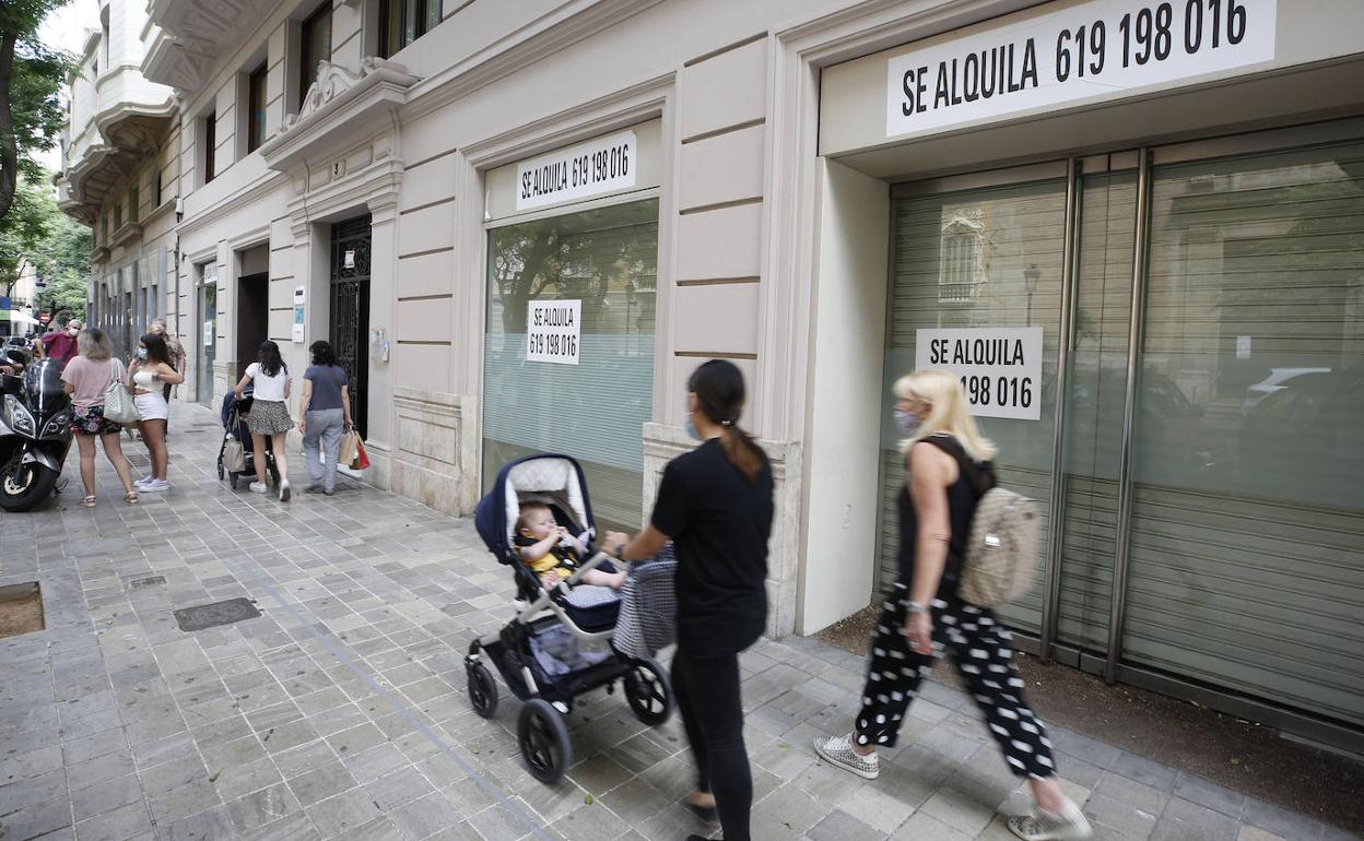 Dos mujeres pasan ante un bajo comercial desocupado. 