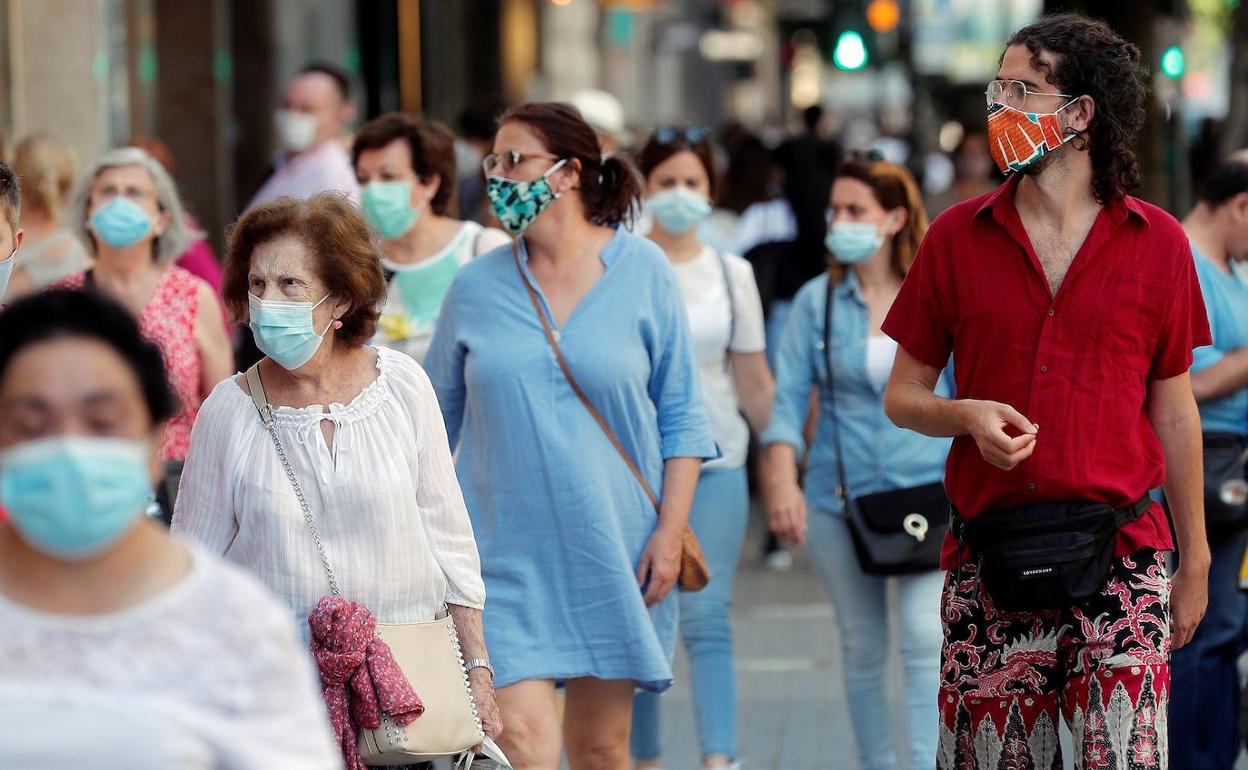 Transeuntes con mascarilla en Valencia. 