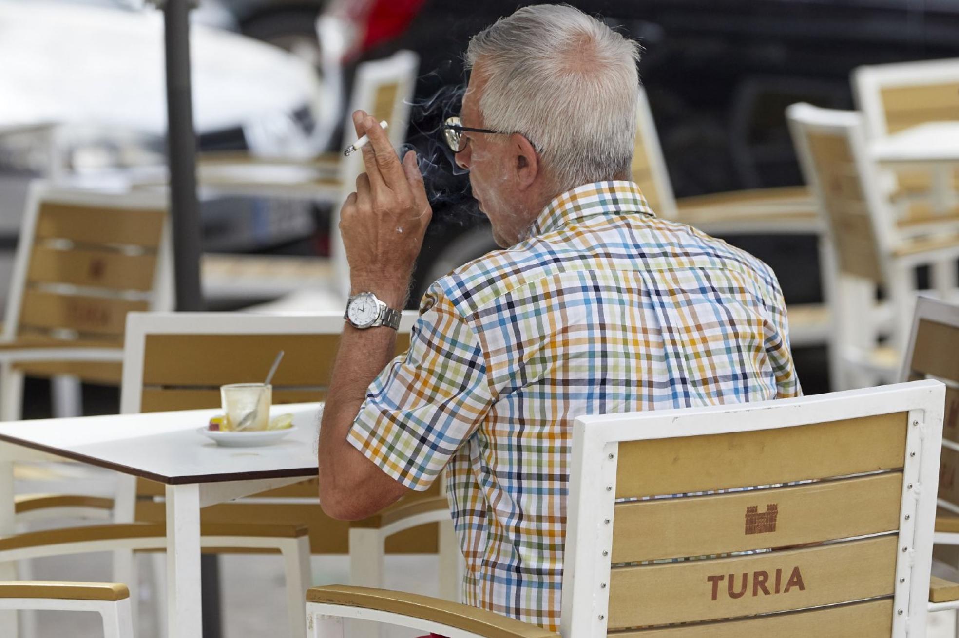  Un joven fuma sentado en un un portal. IrlandisTerraza. Un ciudadano fumando en la terraza de un bar. IVÁN ARLANDIS