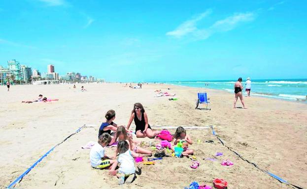 Una familia en un espacio parcelado de la playa de Gandia. 