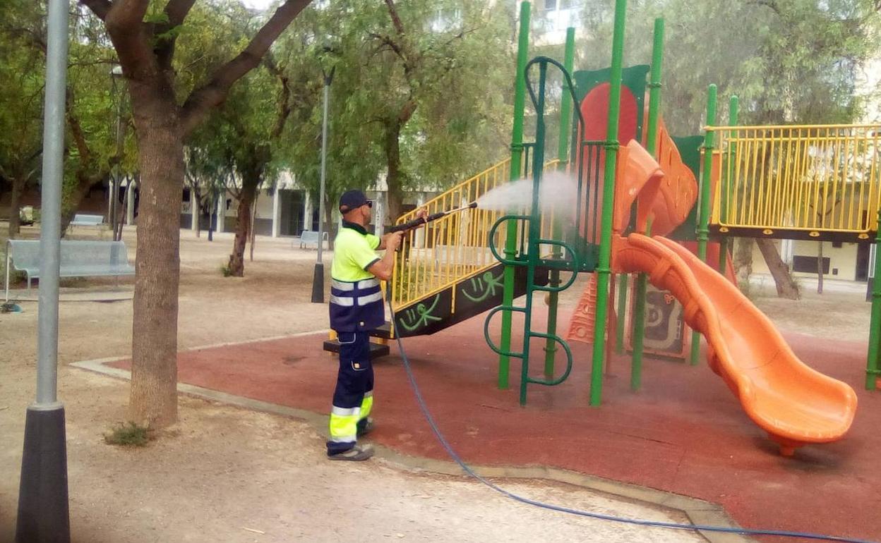 Un operario municipal realiza trabajos de limpieza en un parque infantil. 