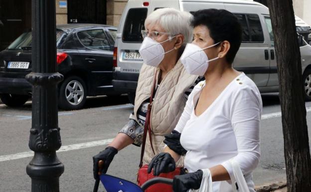 Dos mujeres con mascarilla higiénica en una calle de Valencia.