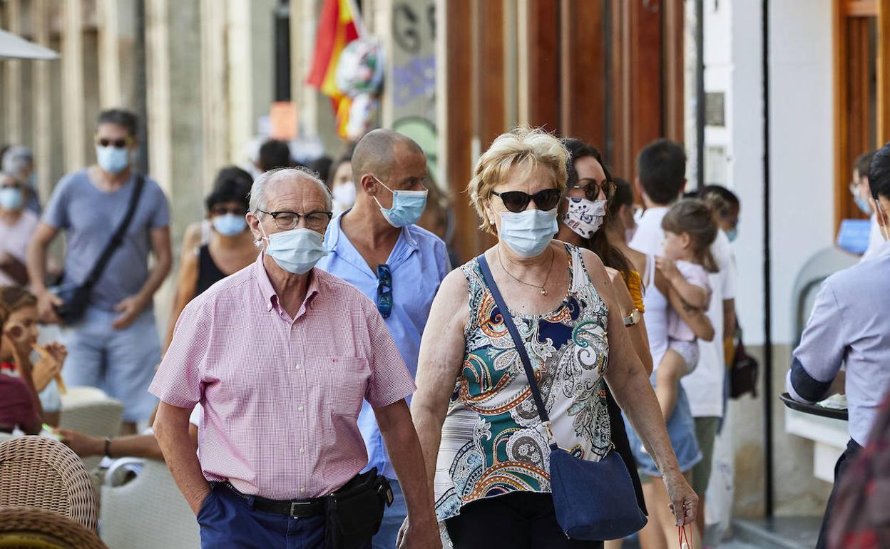 Ciudadanos pasean con mascarilla por el centro de Valencia.