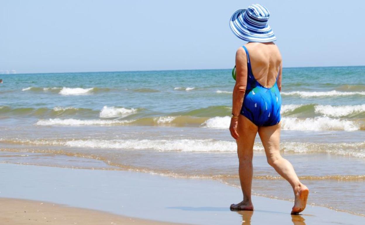 Mujer pasenado por la orilla.