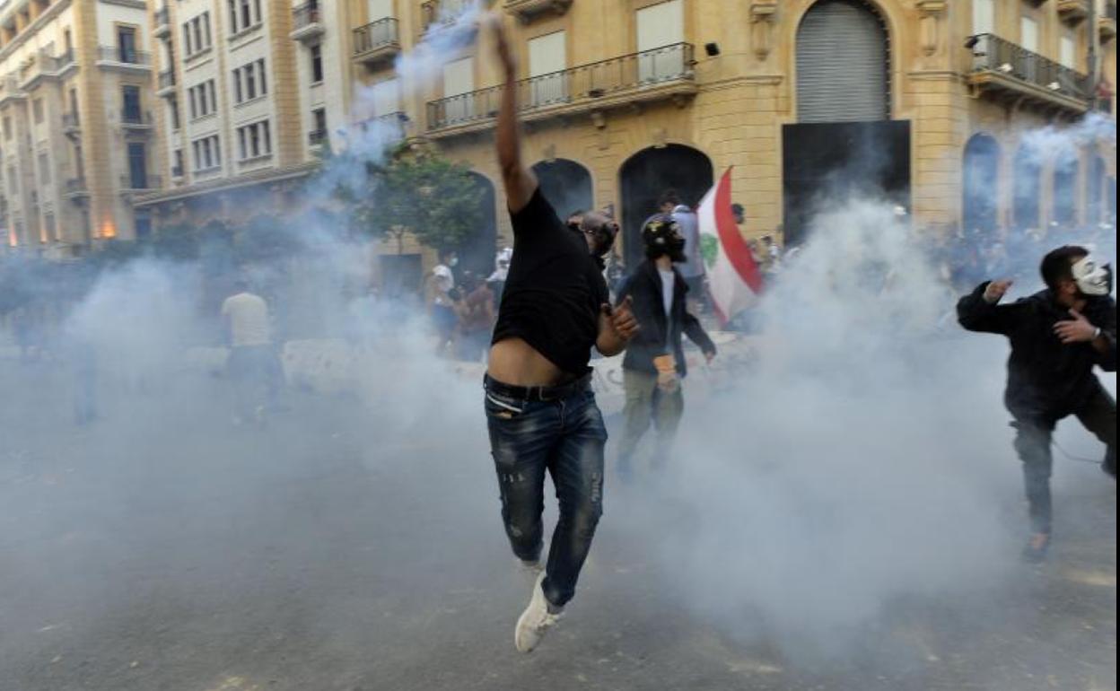 Un manifestante arroja una bomba de humo a la Policía en Beirut.