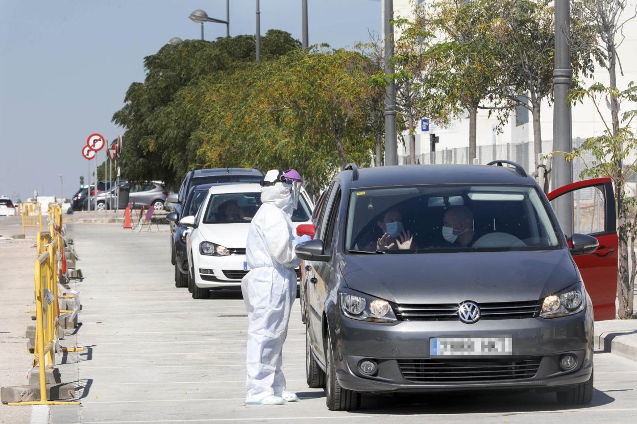 Un profesional sanitario realiza pruebas PCR a los pasajeros de un coche en Valencia.