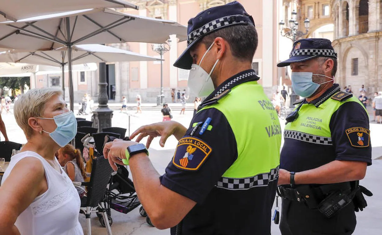 Dos agentes de la Policía Local informan de las nuevas medidas en Valencia. 