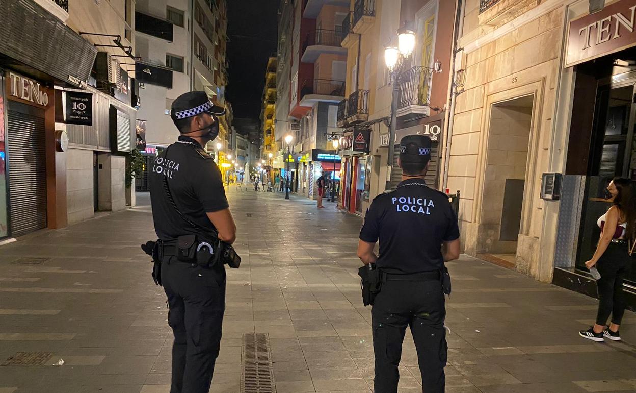 Dos agentes vigilan una de las principales calles de Alicante de madrugada. 