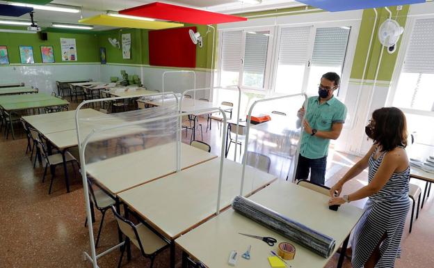 Xavi Leal y Carolina Ramos, director y jefa de estudios, del CEIP Jaume I de Catarroja, colocan los parabanes con los que separar los espacios en el comedor del colegio. 