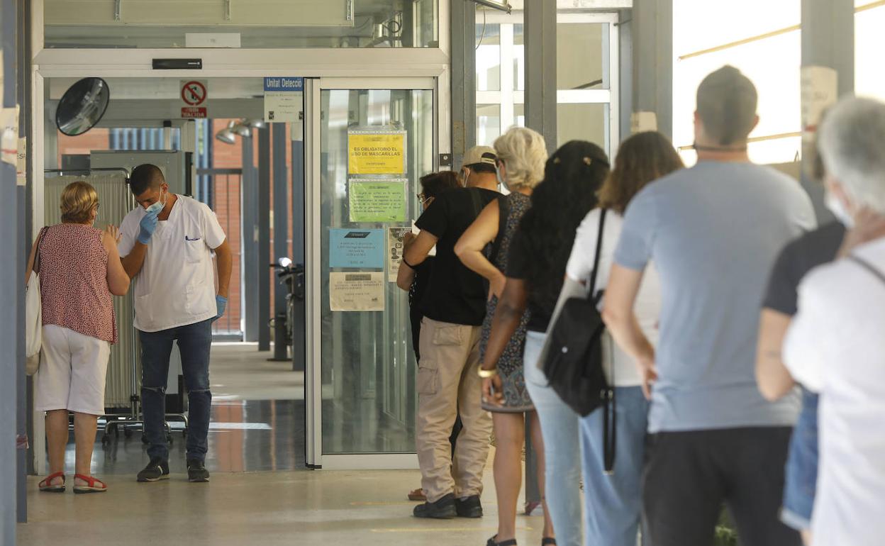 Numerosos pacientes esperan en la cola para acceder al centro de salud de la calle Serrería en Valencia. 