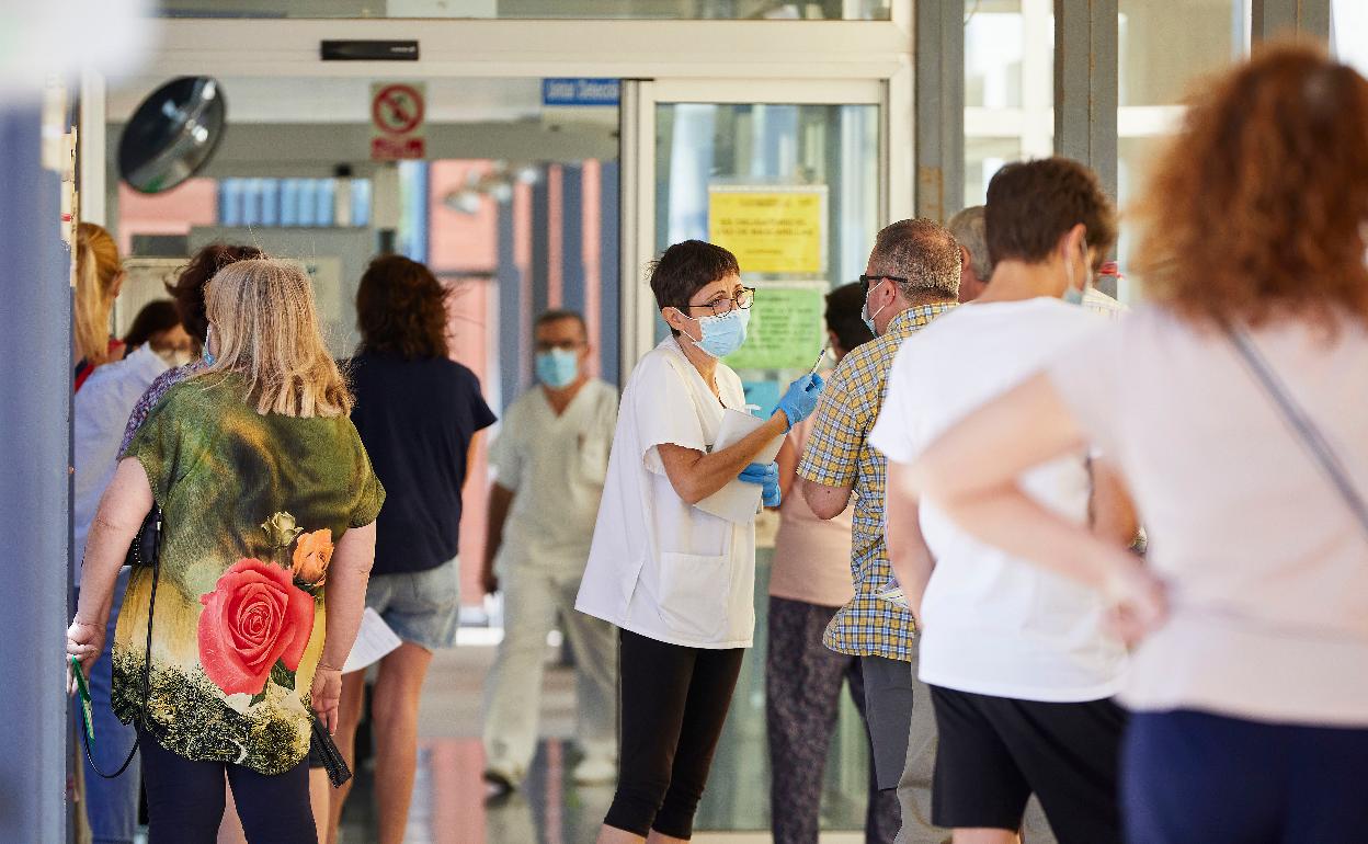 Varias personas esperan su turno en la cola para poder acceder al centro de salud de la calle Serrería en Valencia. 