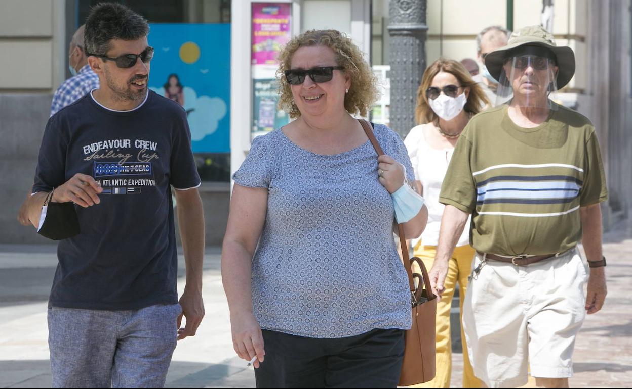 Gente con y sin mascarilla paseando por la calle.