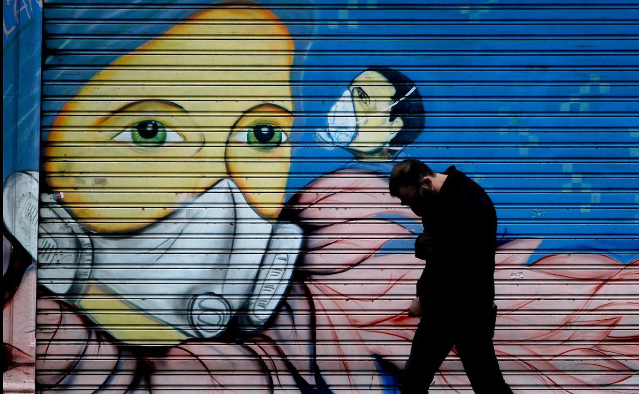 Un hombre camina frente a un mural.