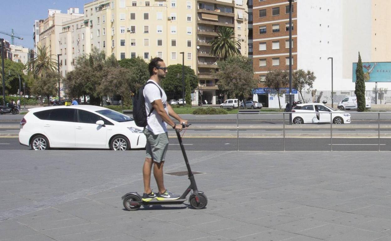 Un hombre pasea con patinete por Valencia, antes de la pandemia.