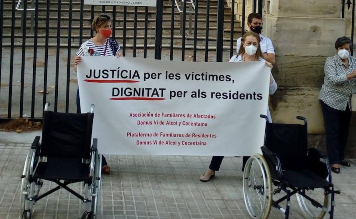 Pancarta de la protesta y algunos de los asistentes, ayer.