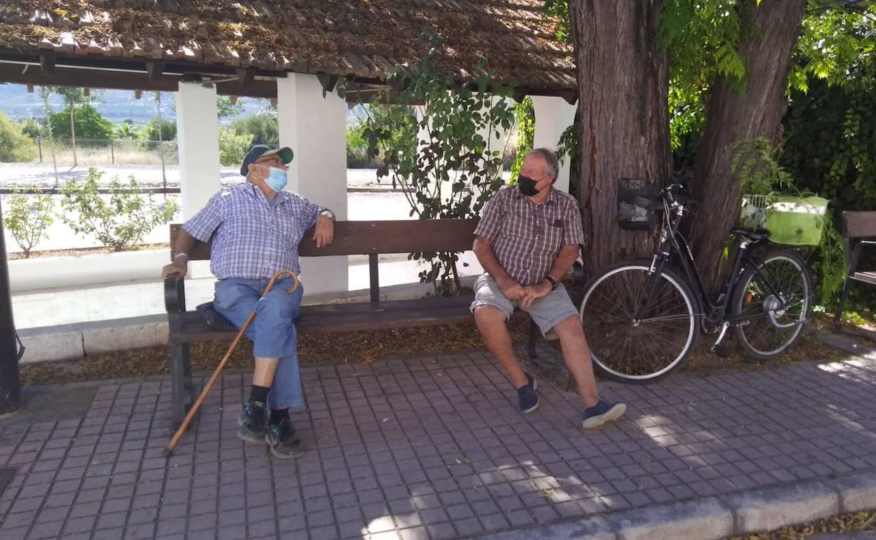 Dos mayores de Cerdà recuperan su charla diaria en el banco, cumpliendo con las medidas de seguridad sanitarias.