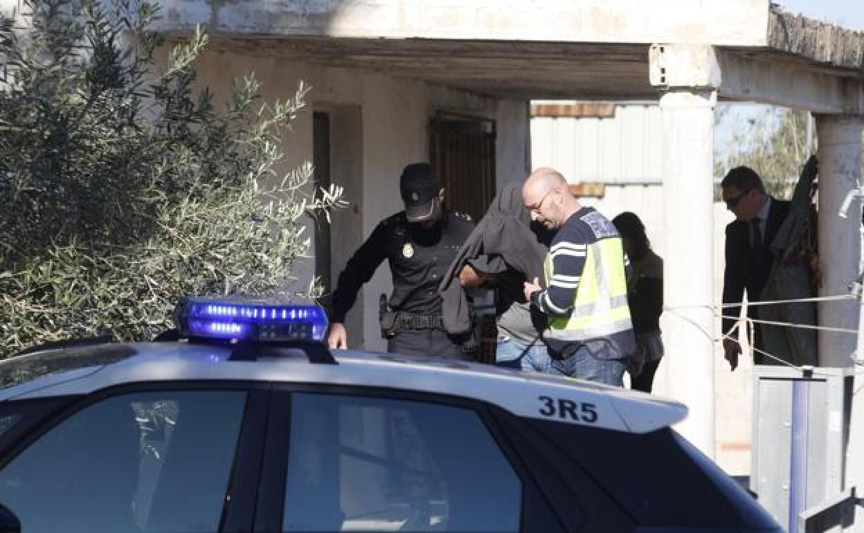 El asesino confeso de Patraix sale con la cara tapada de la casa de campo donde escondió el arma homicida.