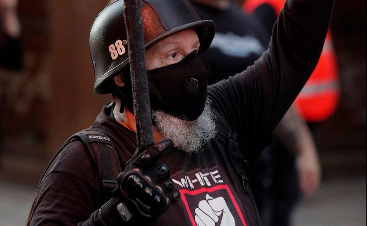 Un manifestante con una camiseta con el lema «White lives matter» realiza un gesto durante la «marcha de las antorchas» convocada por España 2000 en la plaza de Benimaclet.