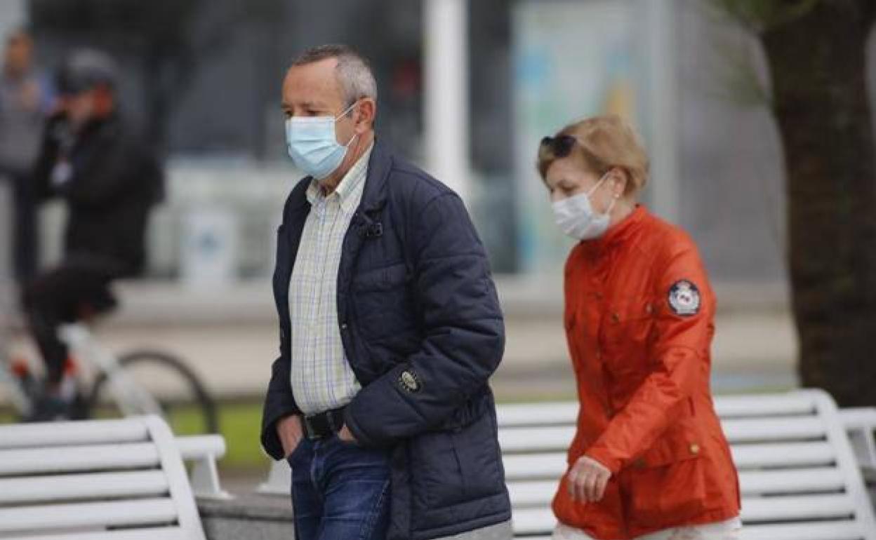 Un hombre y una mujer pasean con mascarilla. 