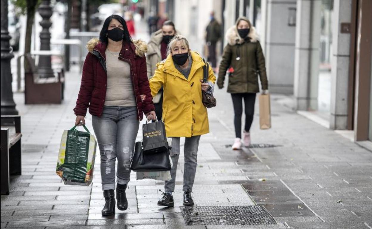 Dos mujeres caminan por la calle con mascarilla.