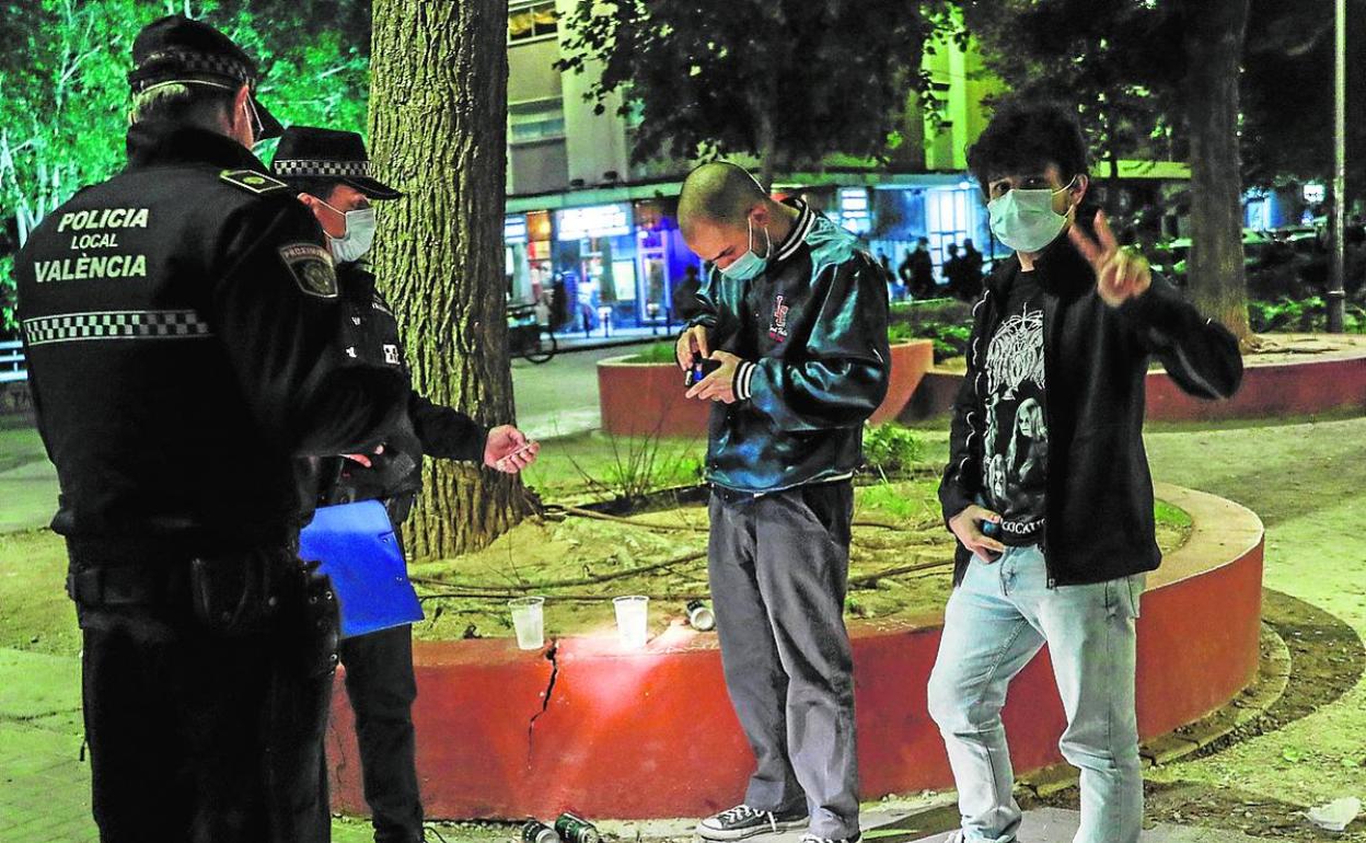 Dos policías identifican a jóvenes con bebidas en la calle en Valencia. 