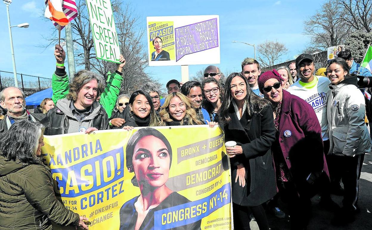 Alexandria Ocasio-Cortez posa junto a sus seguidores y una pancarta con su rostro tras una visita dominical a su distrito electoral.