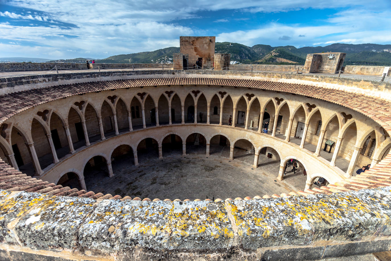 Castillo de Bellver (España). Su estructura destaca por ser circular. Tiene tres torreones y una torre del homenaje que está dividida en cuatro plantas. En el interior del castillo hay un patio de armas de dos pisos que es circular y un patio construido sobre un aljibe. En la segunda planta hay una capilla.