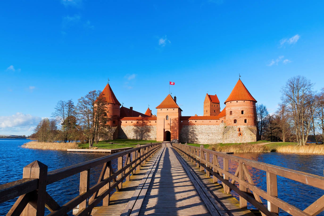 Castillo de Trakai (Lituania). El edficio está formado, actualmente, por dos castillos: el original, muy pequeño, situado a un lado del lago y el otro, erigido en siglos posteriores, ubicado en medio de las aguas. De estilo gótico, el castillo ofrecía una serie de galerías de madera, paneles de vidrieras, murales y pasadizos secretos, que los visitantes pueden ver en el museo oficial del castillo.