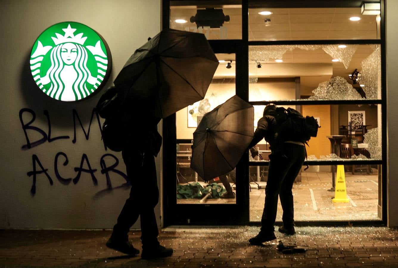 Los manifestantes rompen ventanas e ingresan a una cafetería durante una protesta en Portland, Oregon.