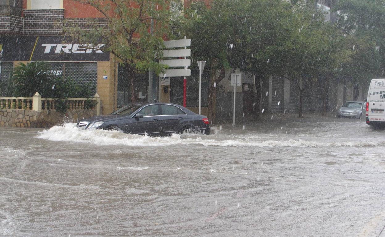 Un coche circulando por una calle de Dénia anegada de agua. 