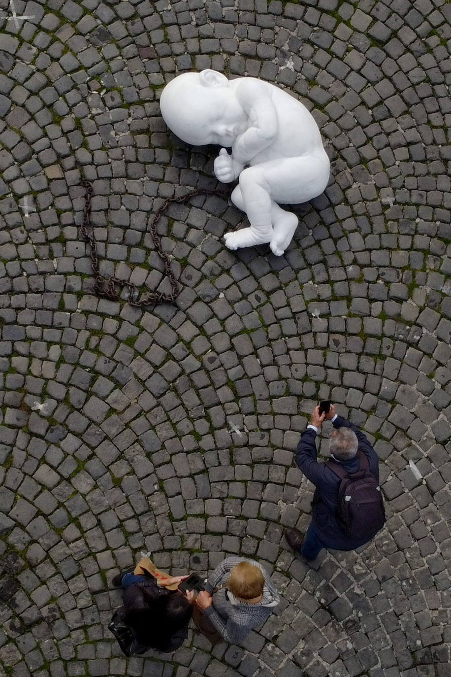 Una escultura en mármol blanco, que representa a un niño acurrucado y con una muñeca encadenada, ha sido abandonada en el centro de la plaza Plebiscito, en Nápoles. 