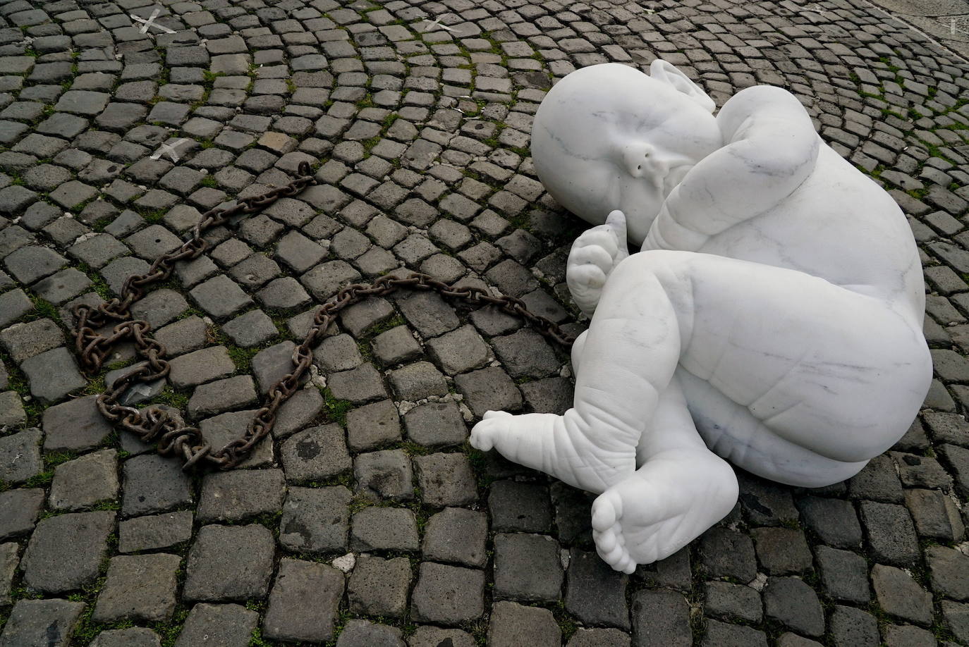 Una escultura en mármol blanco, que representa a un niño acurrucado y con una muñeca encadenada, ha sido abandonada en el centro de la plaza Plebiscito, en Nápoles. 