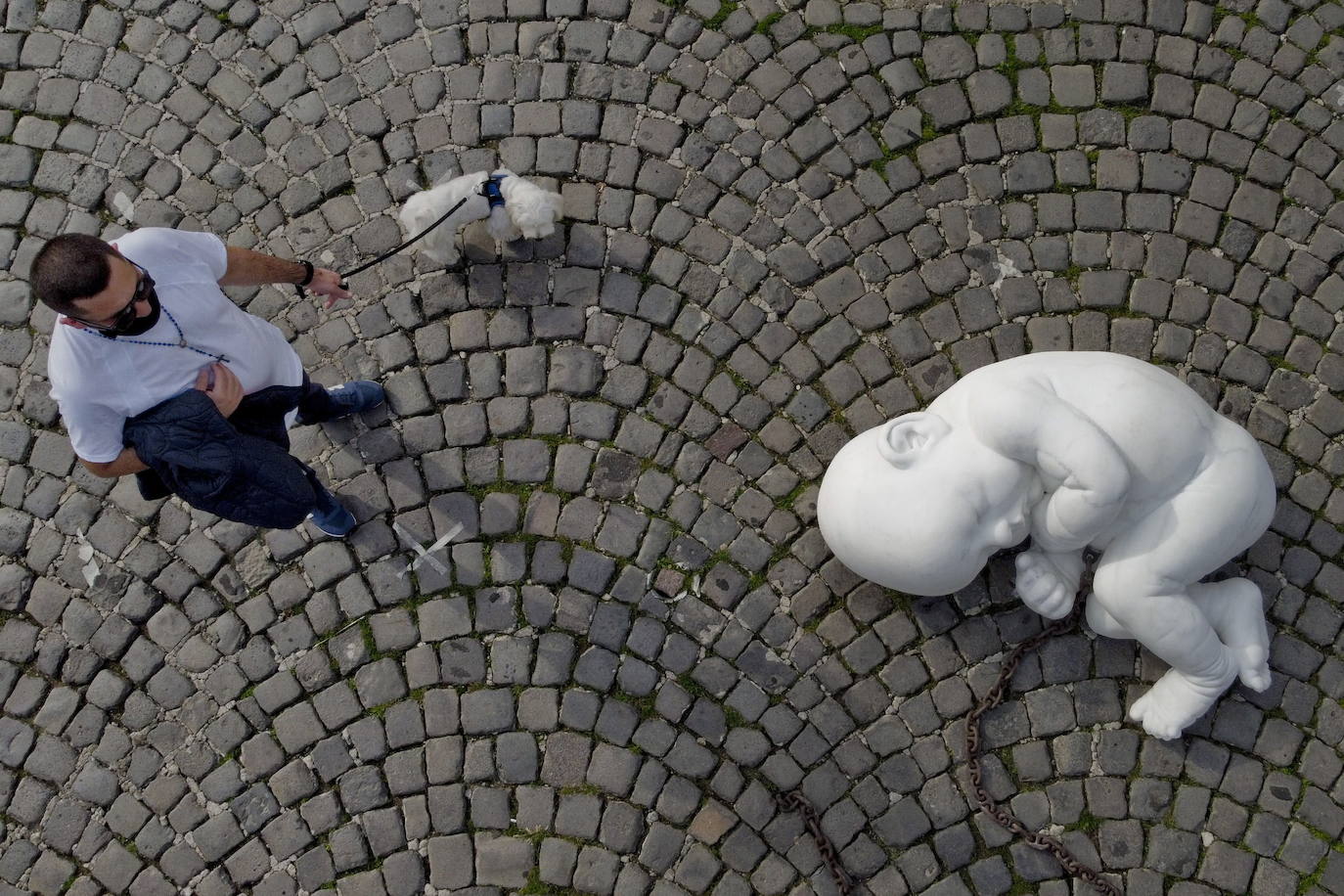 Una escultura en mármol blanco, que representa a un niño acurrucado y con una muñeca encadenada, ha sido abandonada en el centro de la plaza Plebiscito, en Nápoles. 