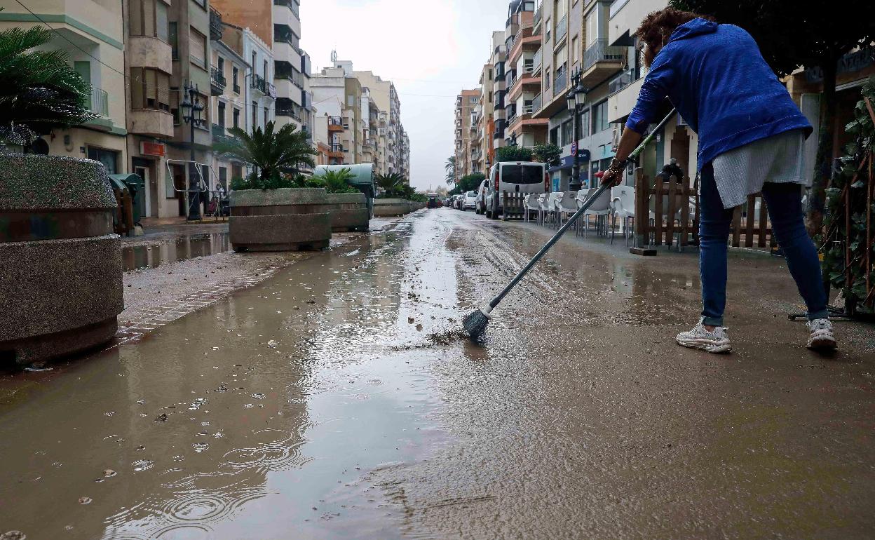 Una mujer limpia el barro en Benifaió tras las lluvias. 