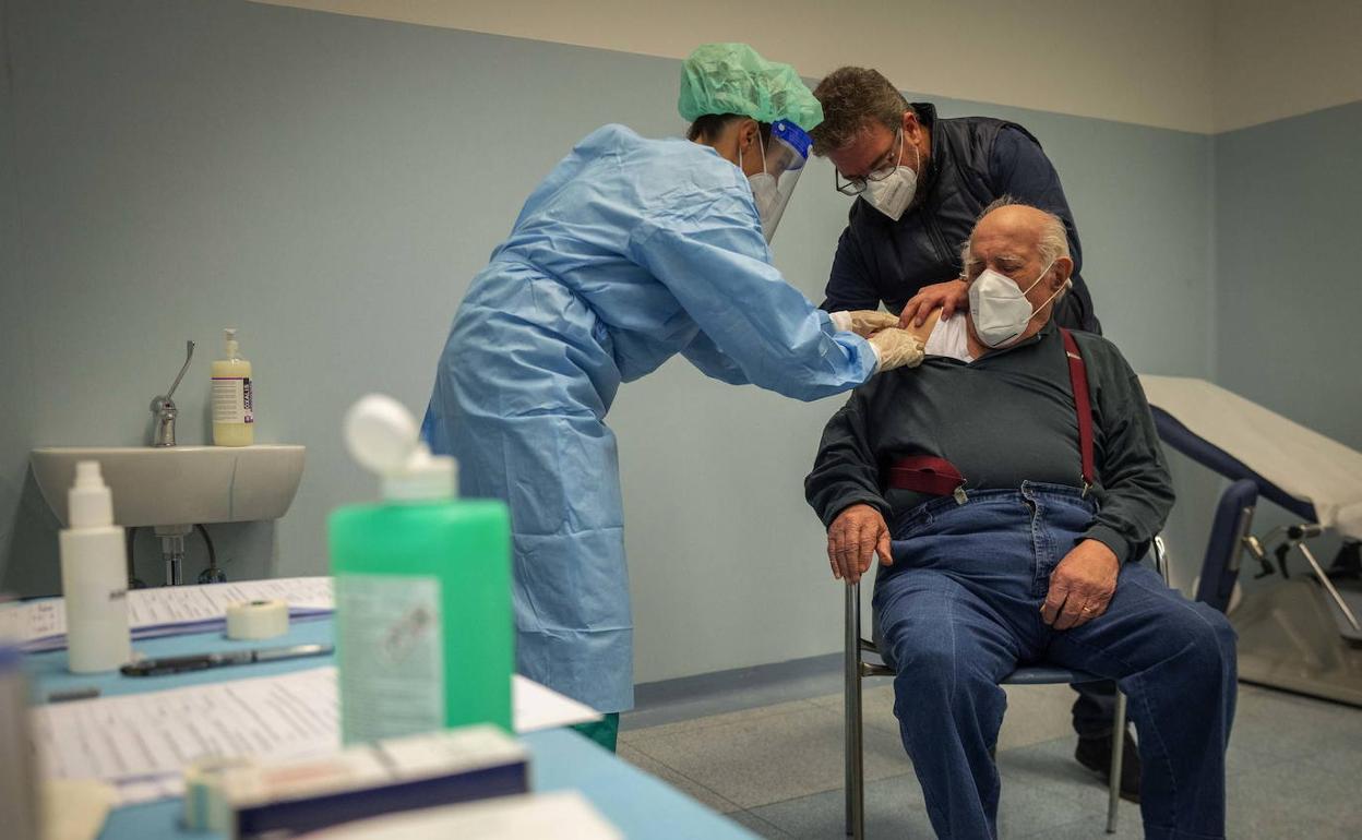 Una sanitaria vacuna a un paciente.