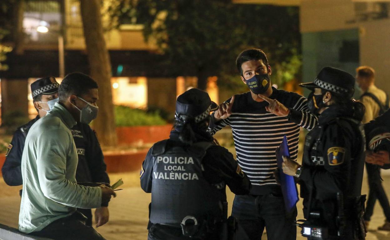 La Policía Local de Valencia, junto a unos jóvenes, al declararse el toque de queda. 