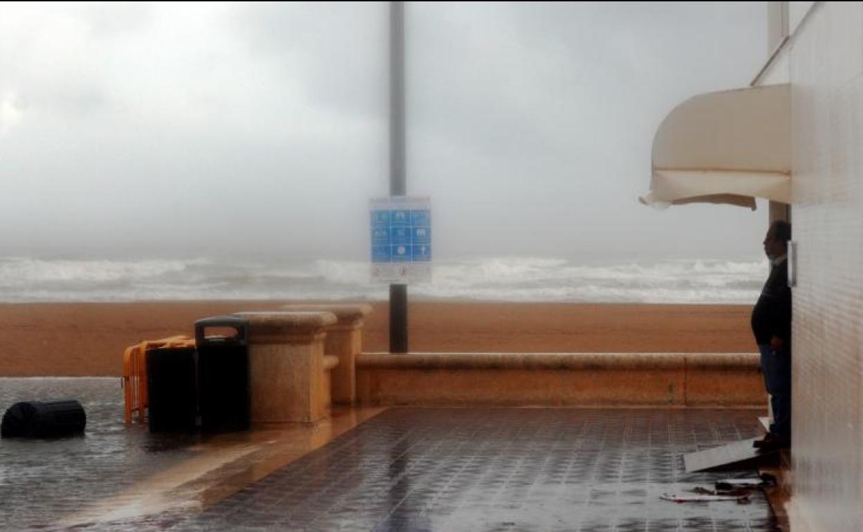 Una persona contempla la intensa lluvia caida este viernes en la ciudad de Valéncia desde uno de los restaurantes de la playa.