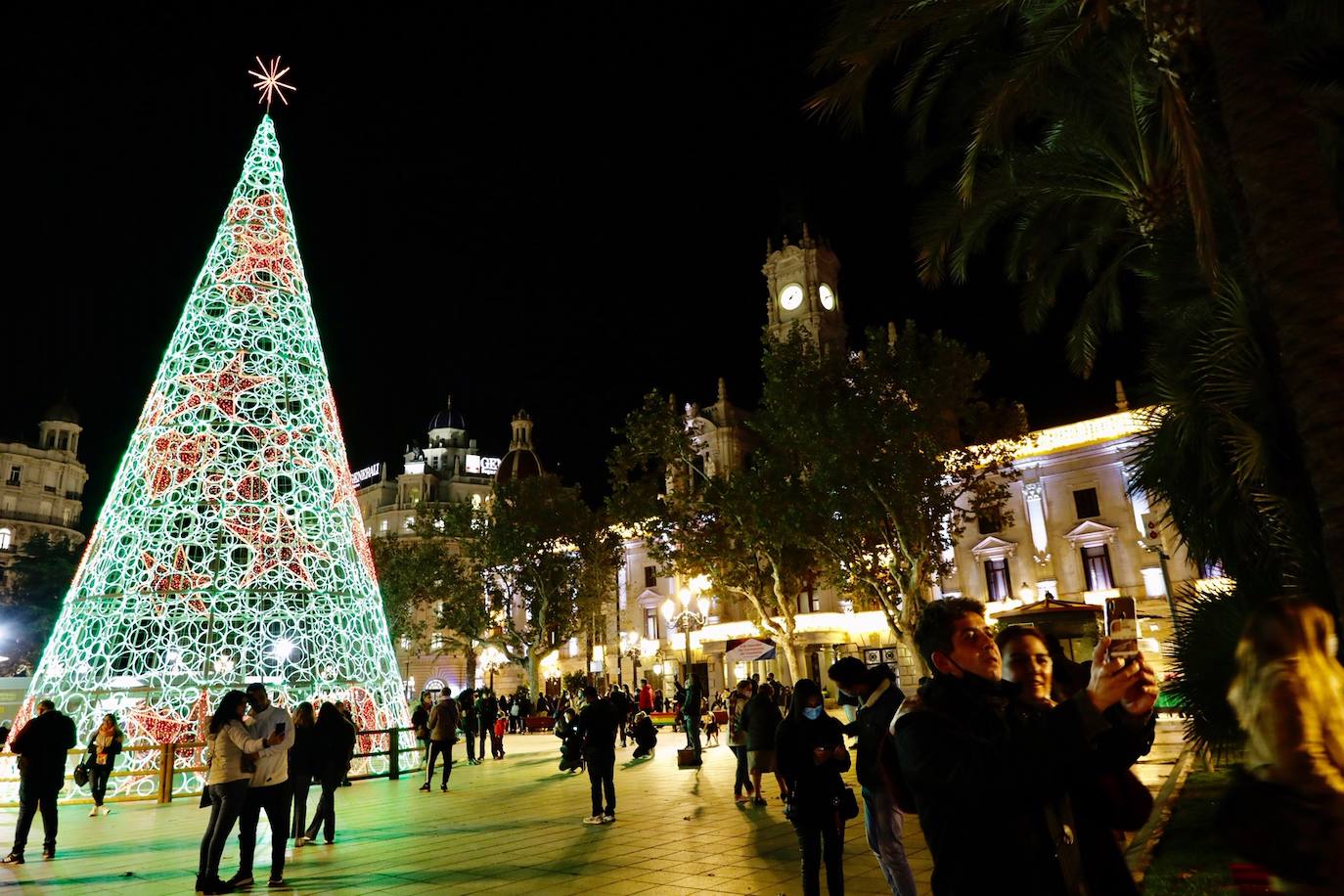 El alcalde Ribó ha asistido esta tarde al encendido en la plaza del Ayuntamiento, acompañado por las falleras mayores de Valencia, Consuelo Llobell y Carla García. La iluminación se estrena en la ciudad con quejas por el escaso gasto frente al aumento en otras ciudades para ayudar al comercio.