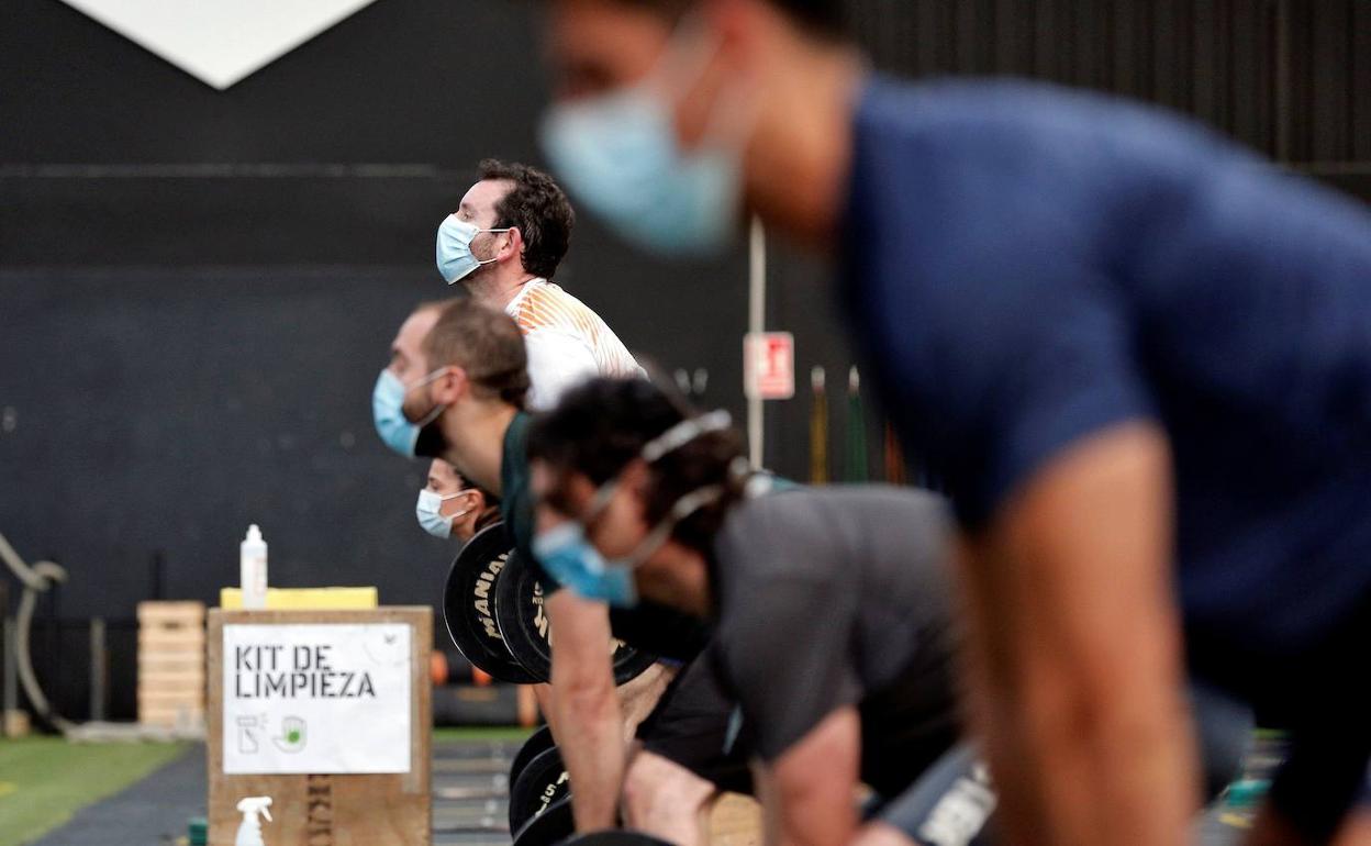 Usuarios de un gimnasio con mascarilla. 