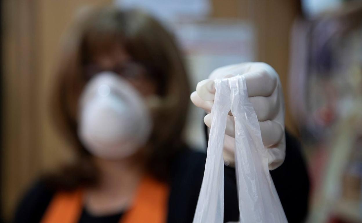 Una persona en su comercio protegida con guantes y mascarilla. 