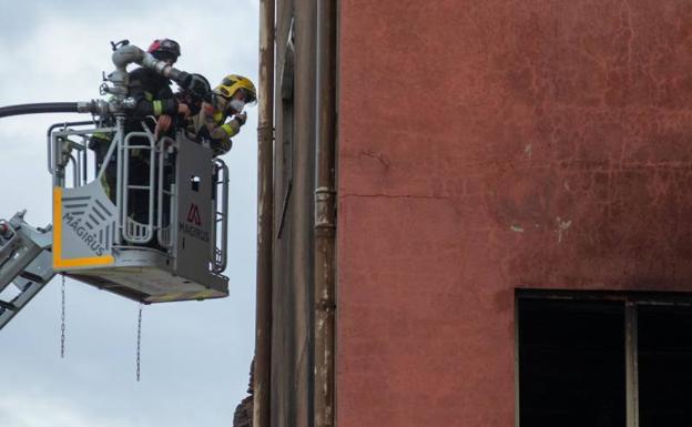 Los bomberos trabajan en el piso superior de la nave industrial de Badalona. 