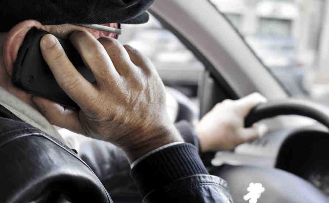 Un hombre conduce mientras utiliza el teléfono móvil.