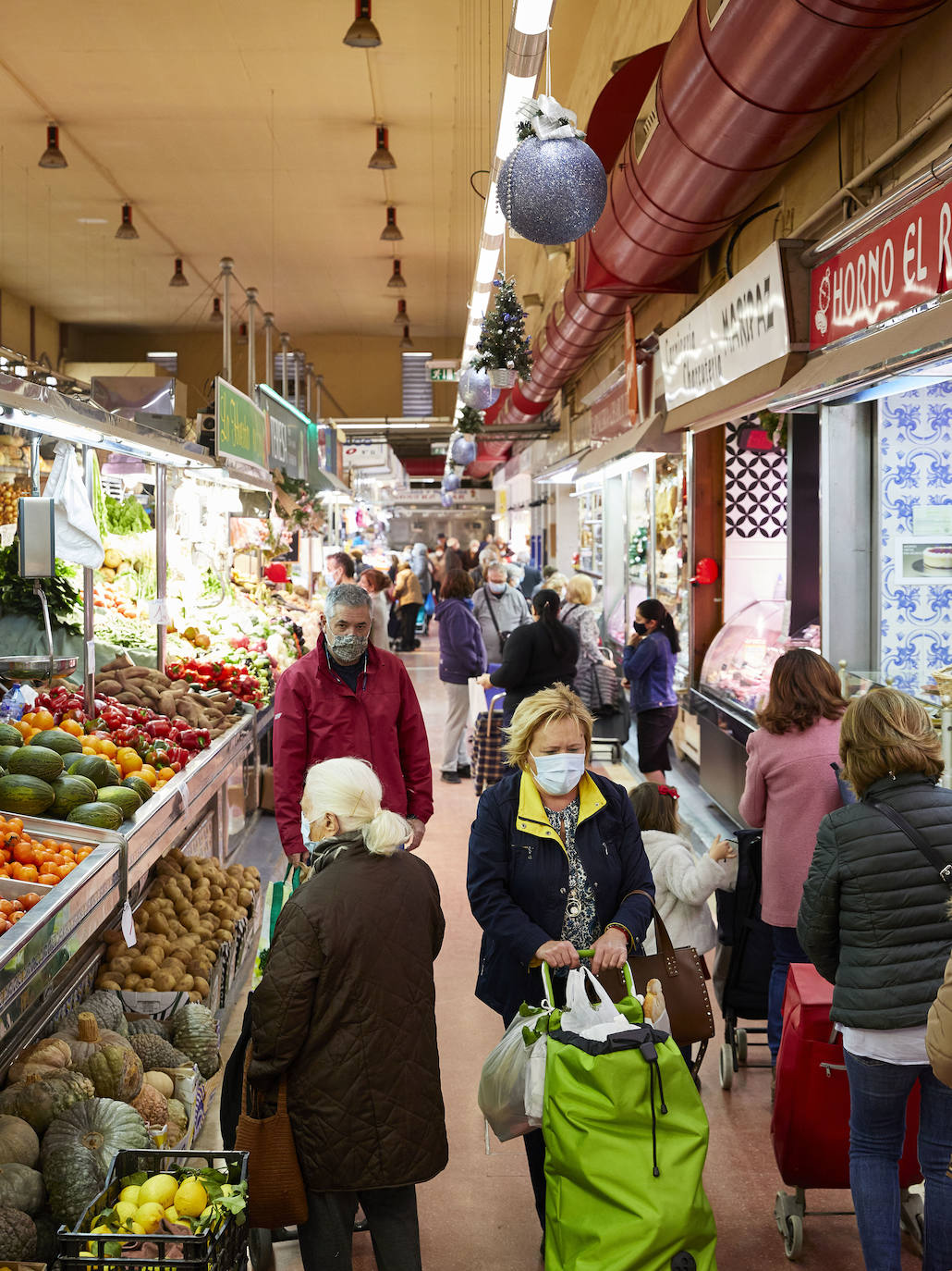 Con la Navidad a la vuelta de la esquina, los valencianos aprovechan para disfrutar del ambiente y realizar las compras en los mercados de la ciudad. La celebración de las fiestas navideñas este año será atípicas y con restricciones por la pandemia del coronavirus. En imagen, el Mercado del Cabaynal este martes.